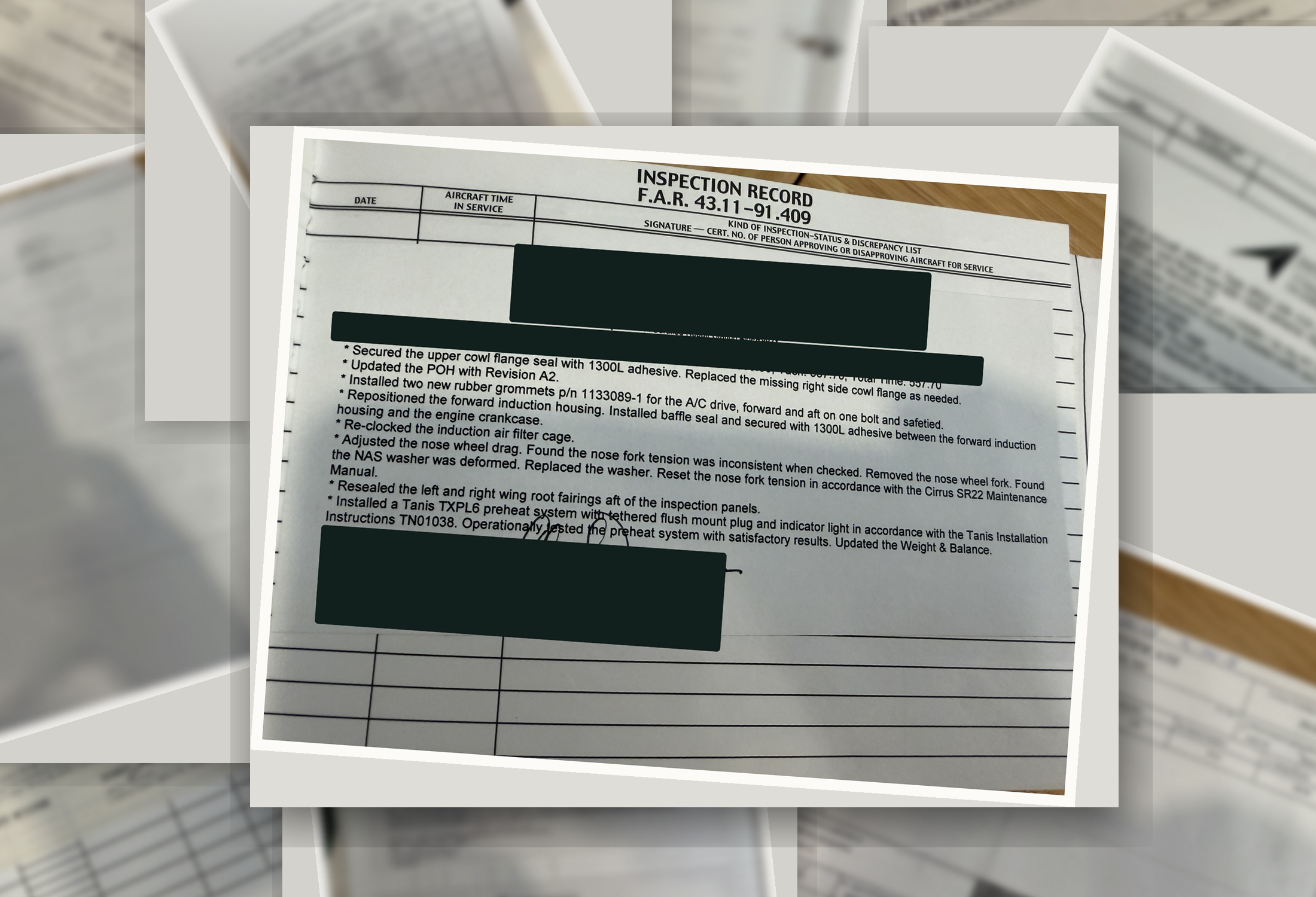 A real paper aircraft logbook page in a three-ring binder over a stack of decades of paper, with identifiers redacted.